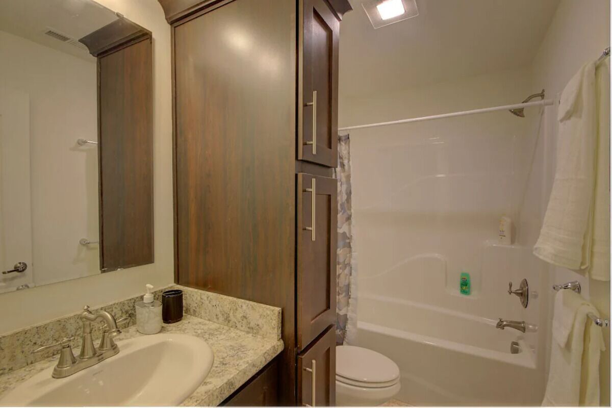 A bathroom with a sink, mirror, cabinet, toilet, and bathtub.
