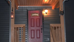 A wooden front door with a red frame, a small porch with a railing, and a lantern on the left.