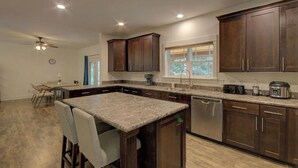 A modern kitchen with granite countertops, dark wood cabinets, a dishwasher, and a window with a view.