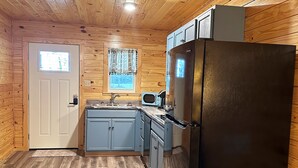 Una cocina pequeña con paredes de madera y un refrigerador negro.