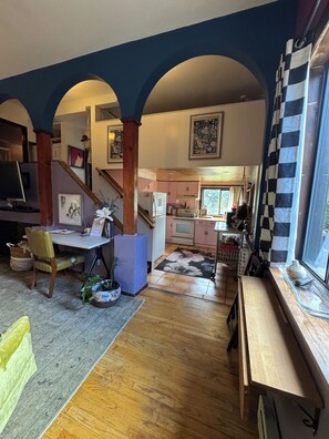 Amplia sala de estar con piso de madera, una mesa de comedor y una cocina al fondo.