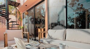 A modern outdoor seating area with a laptop, a plate with cookies, and a mug on a wooden table.