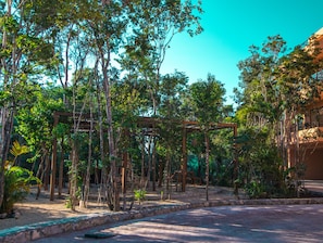 Un patio con una pérgola, árboles y un edificio con balcones.