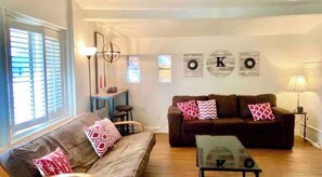 A living room with a brown sofa, a coffee table, and a blue table with a lamp. There are decorative pillows on the sofa and a wall with circular decorations.