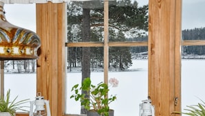 A wooden-framed window with a view of a snowy landscape and a potted plant with a pink flower. - Gorgeous home in Kristinehamn (Kristinehamn)
