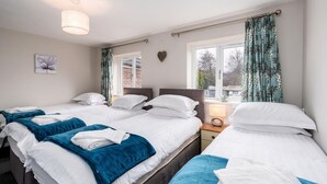 Hotelkamer met twee bedden, een nachtkastje met lamp, een raam met gordijnen en een kunstwerk aan de muur.
