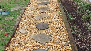 Un sentier bordé de pierres plates qui mène à une maison.