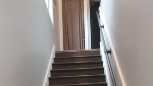 Un escalier en bois, doté d’une rampe, mène à une porte située en haut.