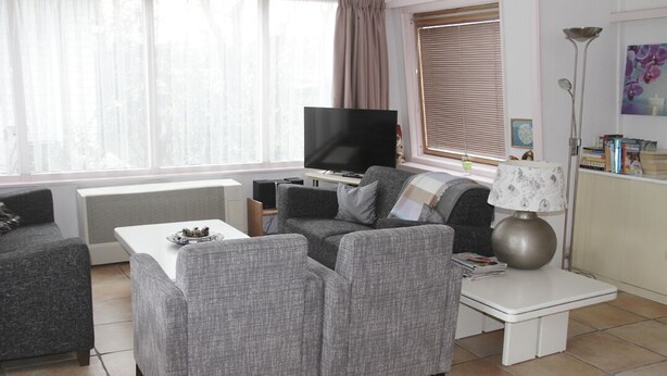 A living room with a grey sofa set, a flat-screen TV, a coffee table, and a lamp.