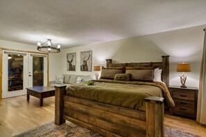 Un dormitorio con una cama de madera, una mesita de noche con lámpara, un sofá y una puerta que da a un balcón.