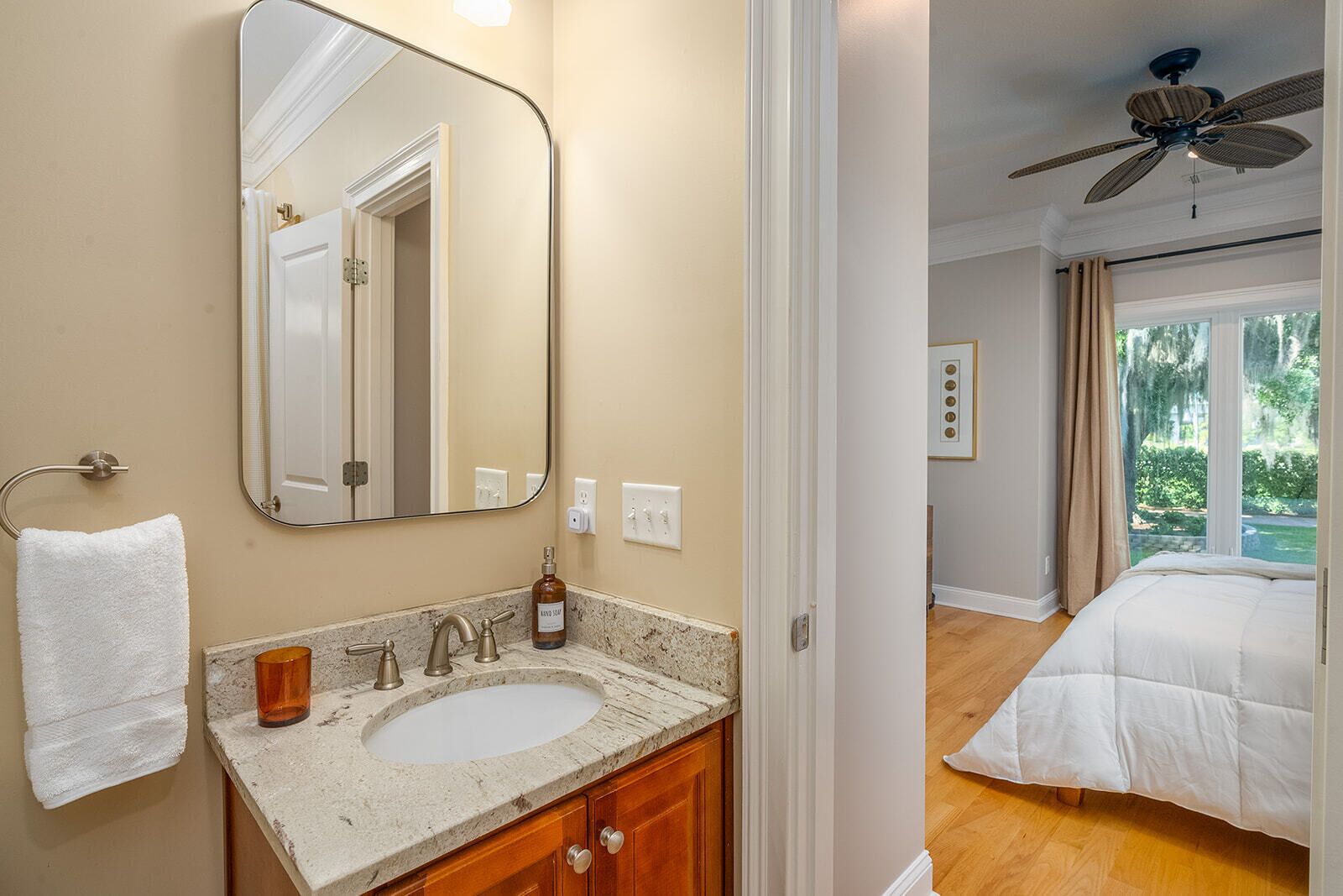 A bathroom with a large mirror, a sink, and a towel rack.