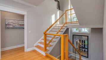 A modern staircase with wooden steps and glass railings, leading to an upper floor.