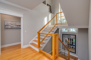 Una escalera moderna con escalones de madera y barandillas de cristal, que conduce a un piso superior.