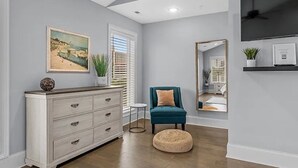 A modern living room with a white dresser, teal armchair, and a round ottoman. - Luxe 4 Story Townhouse w/Elevator, Garage (Myrtle Beach)