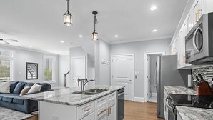 A modern kitchen with white cabinetry, a marble countertop, and stainless steel appliances. - Luxe 4 Story Townhouse w/Elevator, Garage (Myrtle Beach)