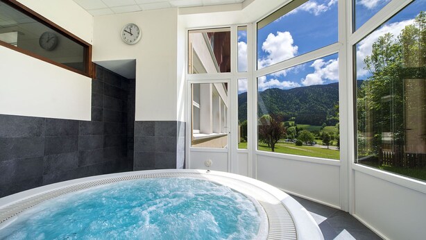 A hot tub with a view of a mountainous landscape through large windows. - L'ESCANDILLE Village Vacances (Autrans-Meaudre-en-Vercors)