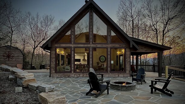 A log cabin with a stone patio, a fire pit, and outdoor seating. - Scenic 7-acre mountain home, seasonal waterfall view, EV charger, dog friendly! (Marion)