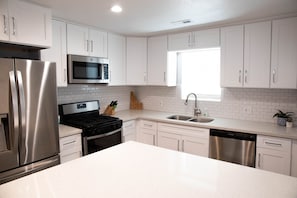 A modern kitchen with white cabinets, stainless steel appliances, a window, and a sink. - Historic Spanish Fork Home  (Spanish Fork)