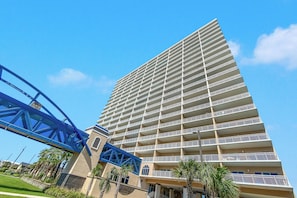Een hoog hotel met meerdere balkons en een blauwe voetgangersbrug.