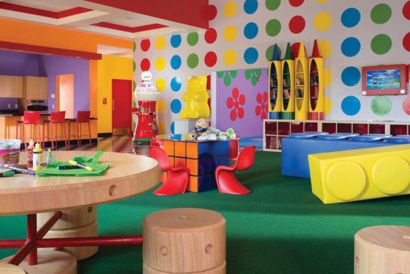 Un área de juegos infantil llena de colores, con una mesa, sillas y diversos juguetes.