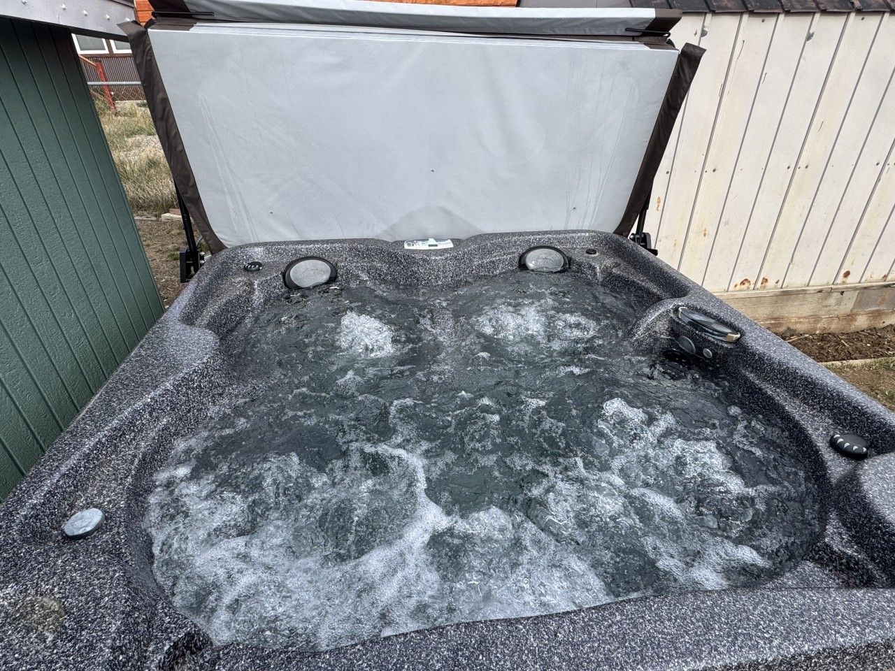 A hot tub with a cover, two jets, and a control panel.
