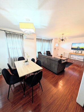 Un salon moderne avec une table à manger, un canapé et un téléviseur.
