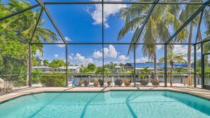 A clear blue pool with a view of palm trees and houses through a metal fence. - Rivers Edge Oasis, Our Secluded Paradise-Sleep 21+ "NEW LISTING" (Fort Myers)