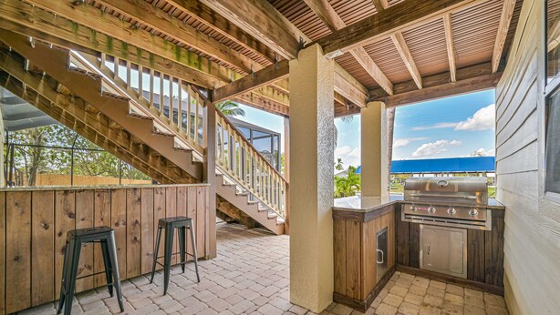 A covered outdoor area with a wooden staircase, a barbecue grill, and two stools. - Rivers Edge Oasis, Our Secluded Paradise-Sleep 21+ "NEW LISTING" (Fort Myers)