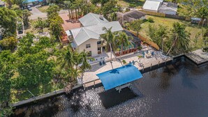 An aerial view of a residential area with a house featuring a large deck, a swimming pool, and a dock extending into a body of water. - Rivers Edge Oasis, Our Secluded Paradise-Sleep 21+ "NEW LISTING" (Fort Myers)