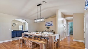 A spacious dining area with a wooden table and benches, a ceiling light fixture, and a clock on the wall. - Rivers Edge Oasis, Our Secluded Paradise-Sleep 21+ "NEW LISTING" (Fort Myers)
