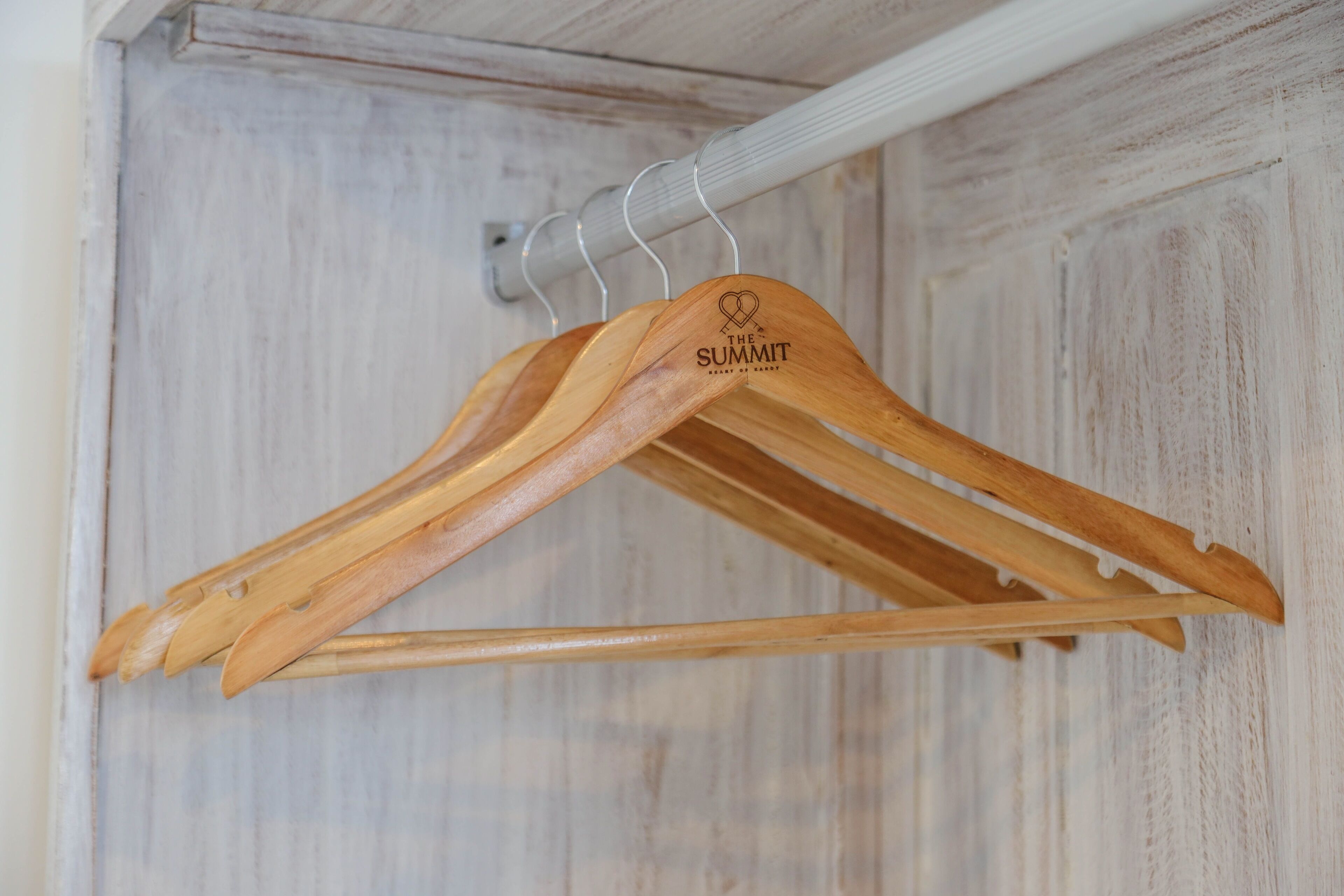 Perchas de madera con un logotipo en una barra de metal.