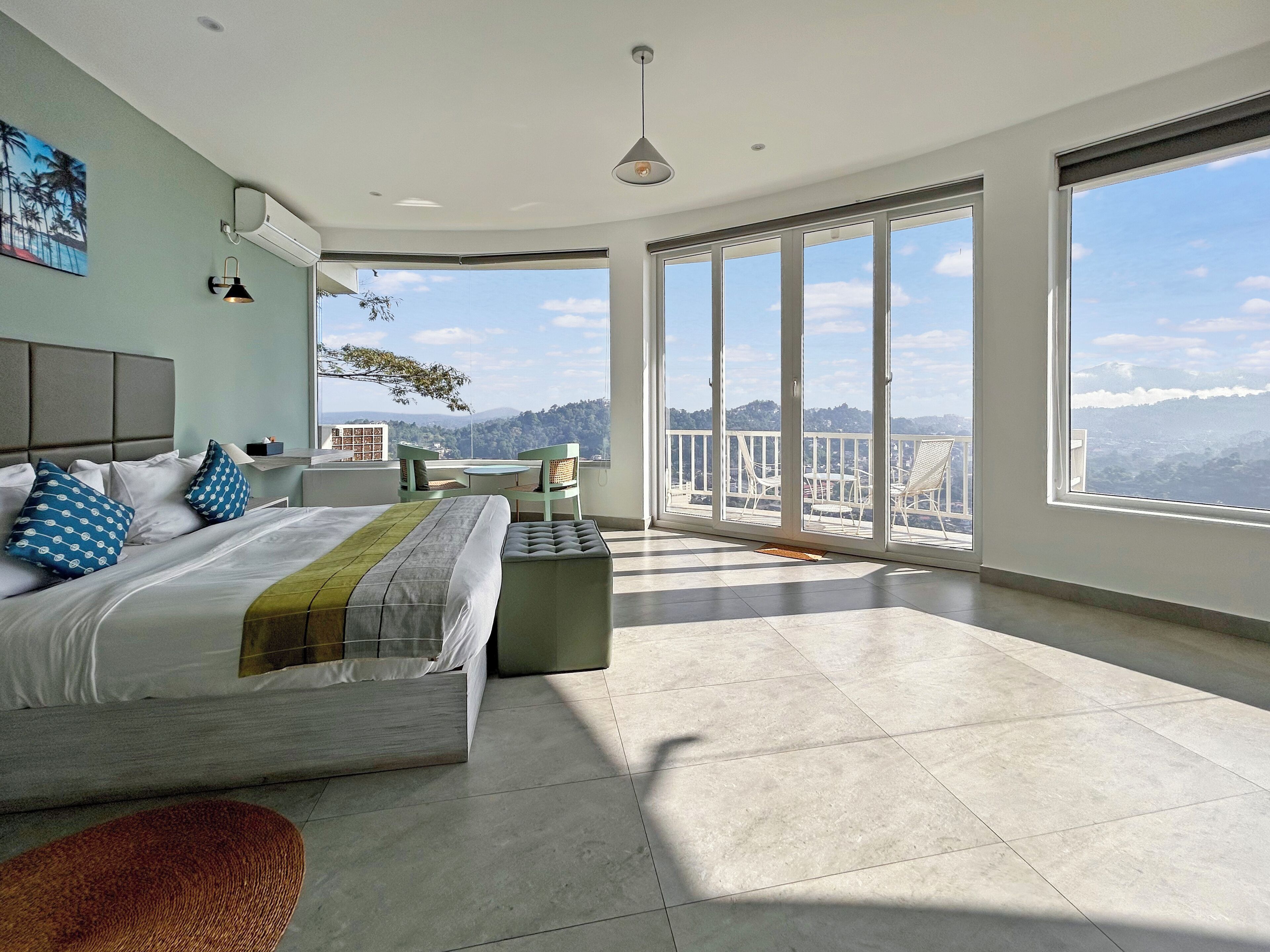 A modern bedroom with a large bed, a balcony with a view, and a dining area.