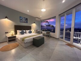 Un dormitorio moderno con una cama grande, mesitas de noche, un banco y un balcón con vistas panorámicas.