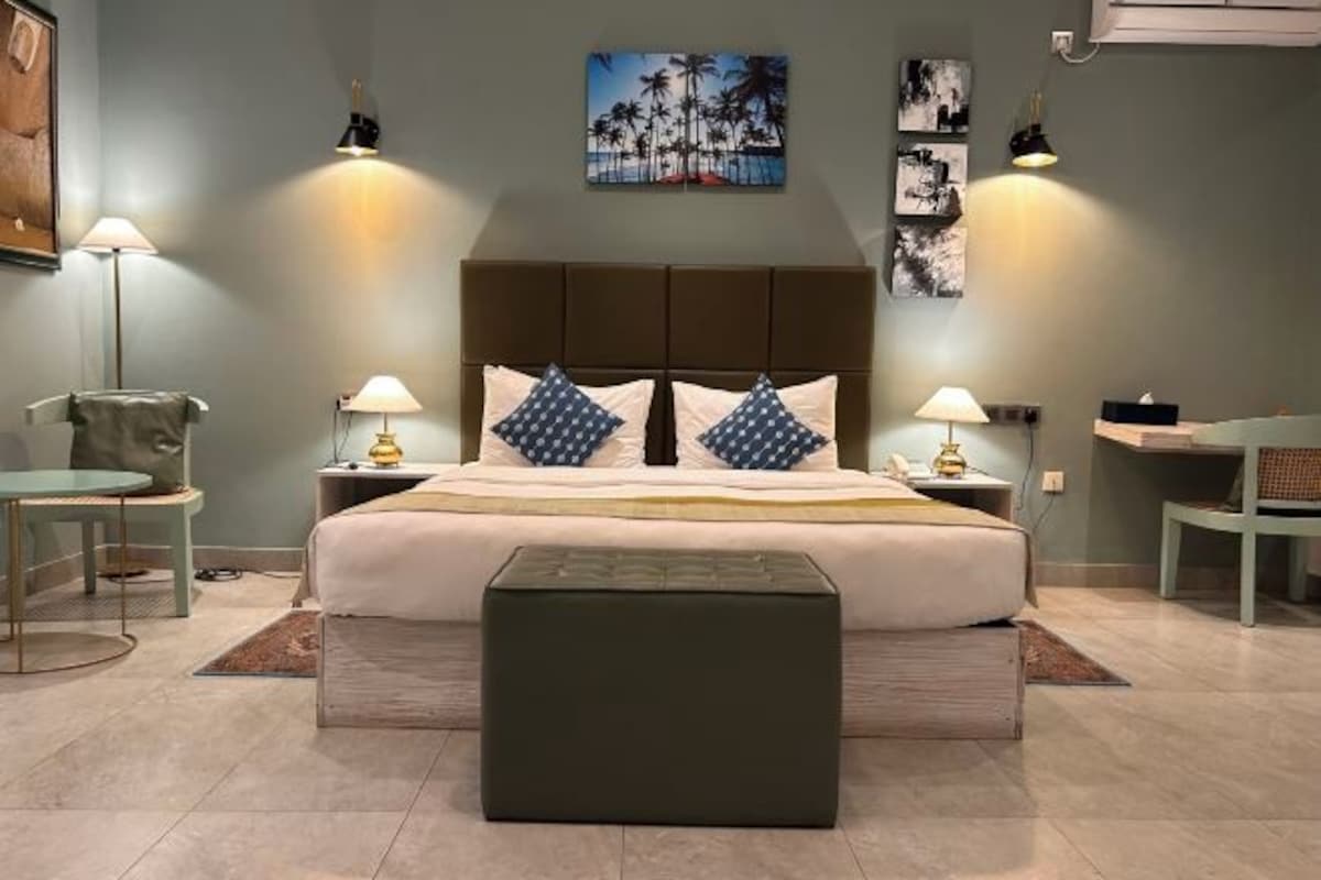 Ein Schlafzimmer mit einem Bett, Nachttischen, einem Sessel und Bildern an den Wänden.