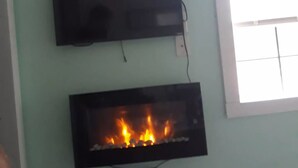 Una stanza con TV a schermo piatto e camino.