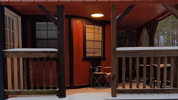 Un portico in legno con tetto in metallo, una panca di legno e un tavolino.