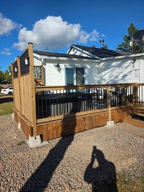 Une maison avec une terrasse en bois, une cheminée et une allée gravillonnée.