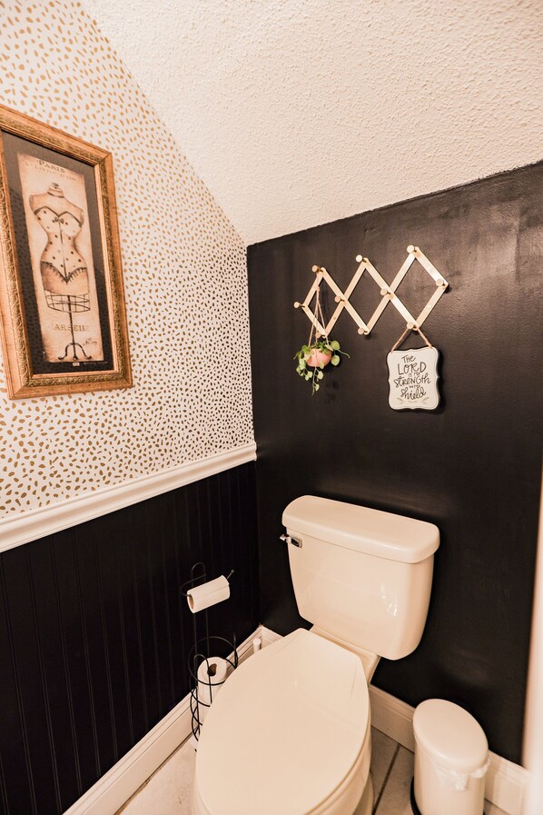 A bathroom with a white toilet, a black wall, and a framed picture on the wall.