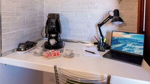 Ein Arbeitsplatz mit Kaffeemaschine, Laptop, Schreibtischlampe und einem Laptop-Bildschirm, der eine Bergblick zeigt.