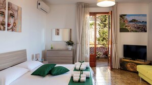 Ein Hotelzimmer mit Bett, Fernseher, Schminktisch, Spiegel und einem Balkon mit Blick.
