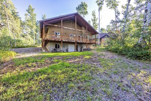Une cabane en rondins à deux étages, dotée d’un balcon et entourée d’une zone boisée.