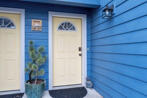 A house with two yellow doors, a welcome sign, a potted plant, and a mailbox.