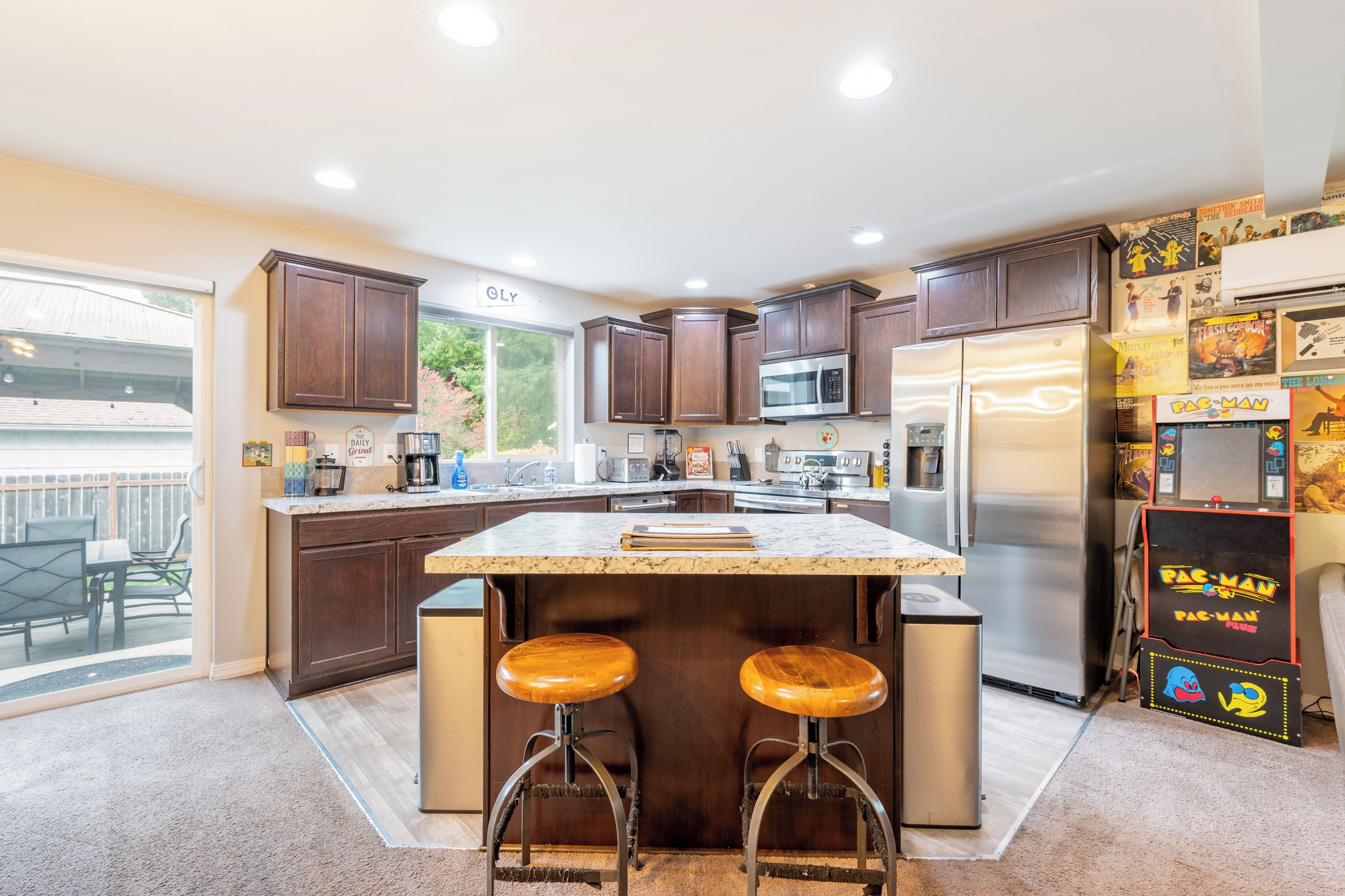 A modern kitchen with dark wood cabinets, stainless steel appliances, and a central island with stools.