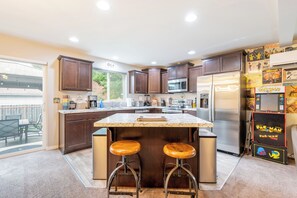 A modern kitchen with dark wood cabinets, stainless steel appliances, and a central island with stools. - The Sizzl-INN' Seagull (Olympia)