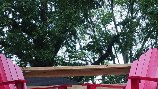 A wooden deck with two red Adirondack chairs and a wooden table. - 2-bedroom vacation home 14 minutes from University of Alabama-Birmingham (Midfield)