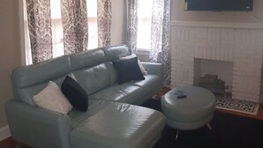 A living room with a light blue sofa, a small round table, and a fireplace. - 2-bedroom vacation home 14 minutes from University of Alabama-Birmingham (Midfield)