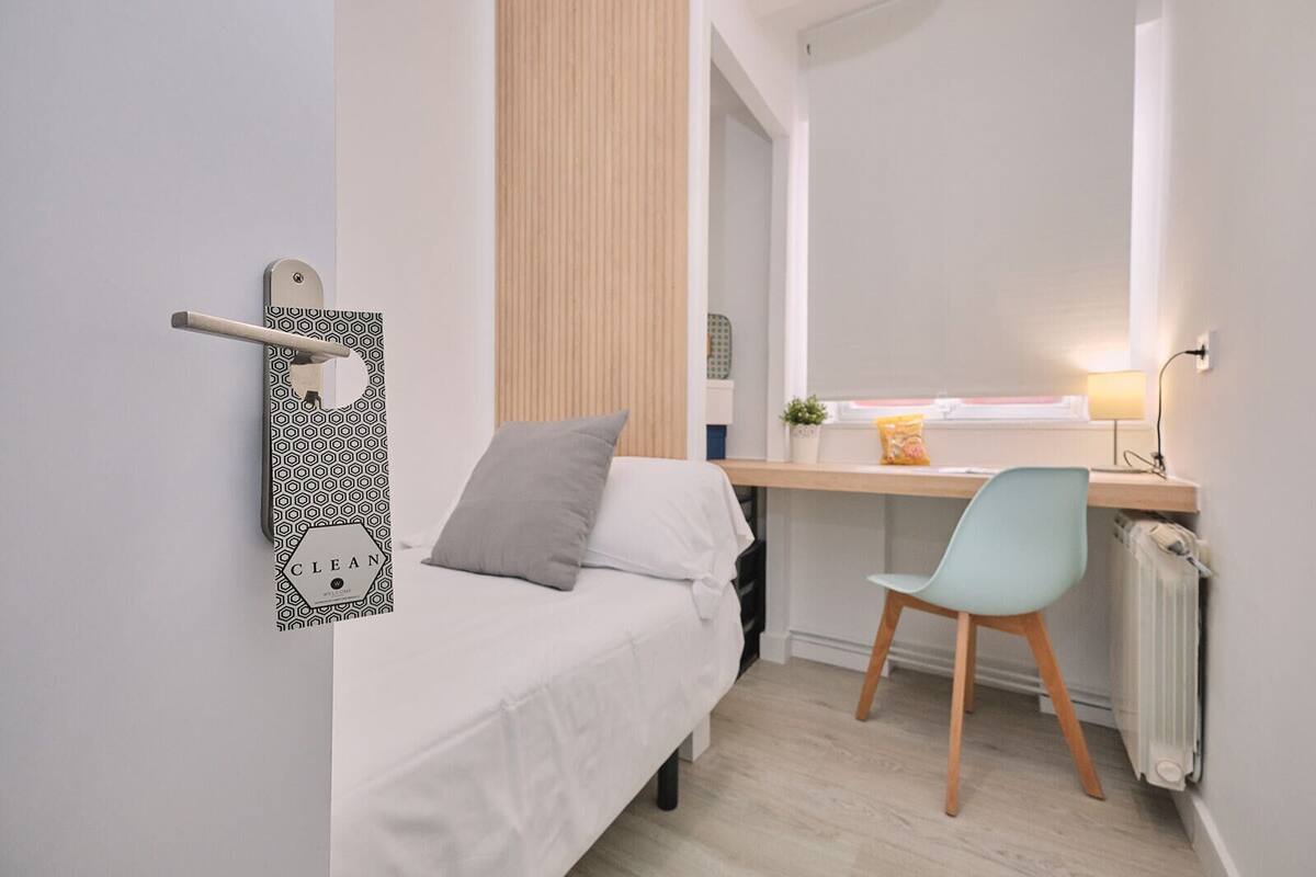 Een compacte, moderne slaapkamer met een bed, bureau en stoel.
