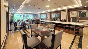 Un hall d’hôtel moderne doté d’un long comptoir d’accueil, d  ’un espace salon et de grandes fenêtres offrant une vue sur l’extérieur.