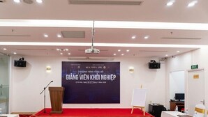 Une salle de conférence équipée d’un pupitre, d’un projecteur, d’un tableau blanc et d’une banderole.