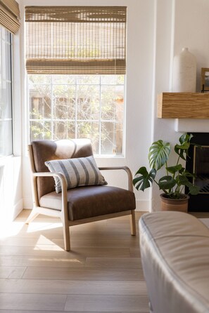 Relax in a serene space with a large window, a comfortable armchair, and a lush potted plant.